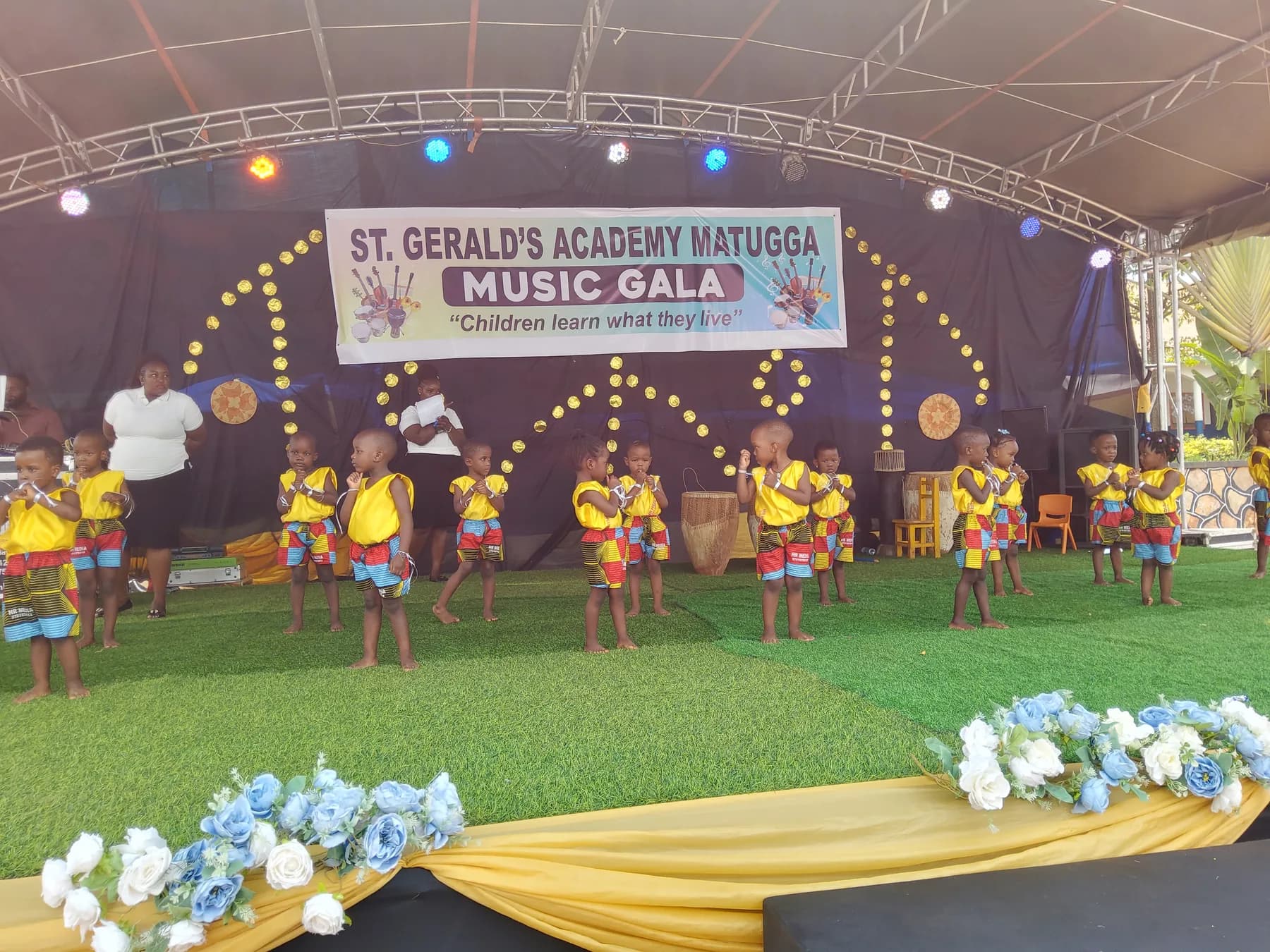 Early-years learners in yellow tops and multicoloured shorts performing in pairs