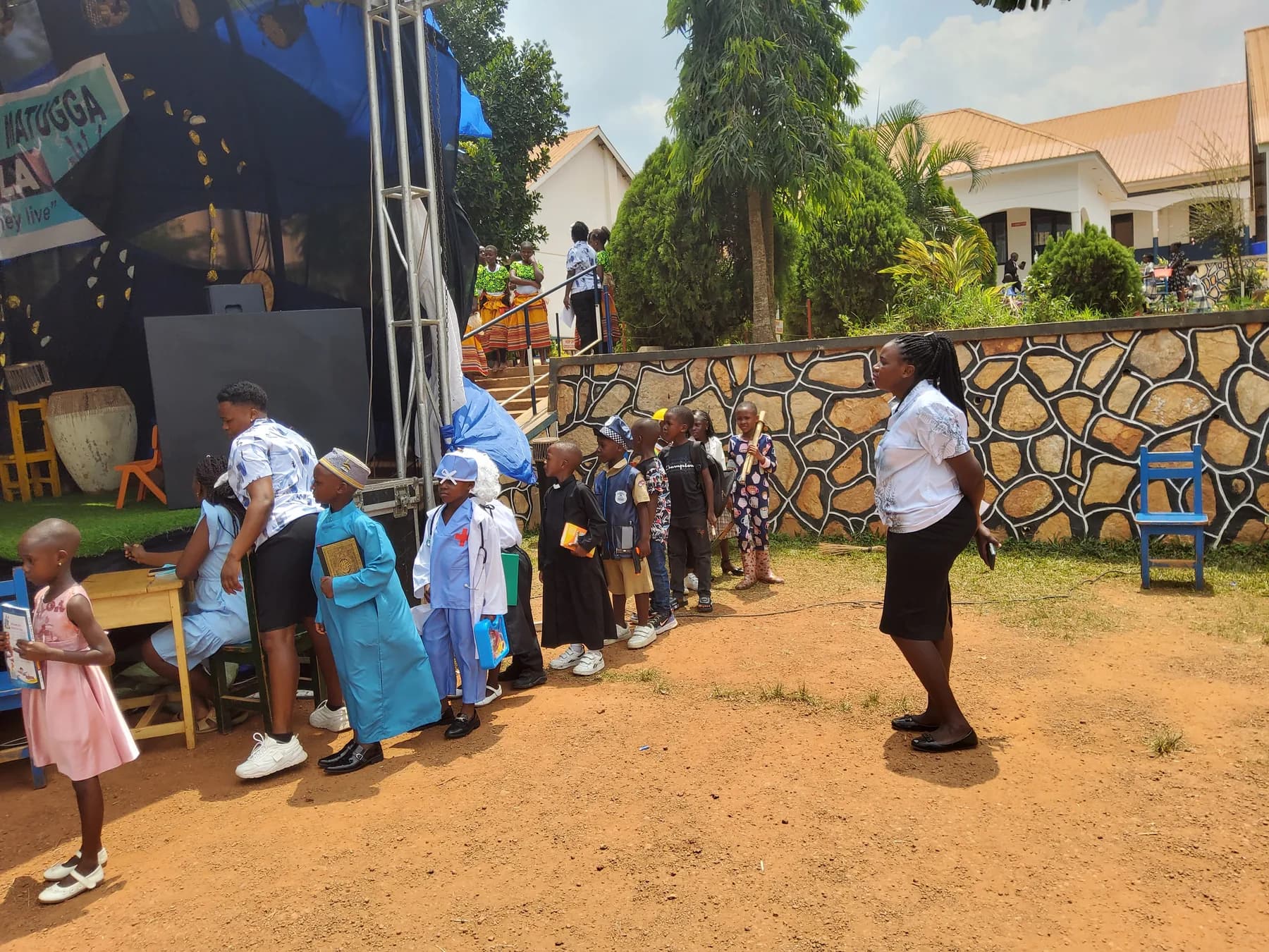 A teacher guiding a line of children dressed as different community professionals