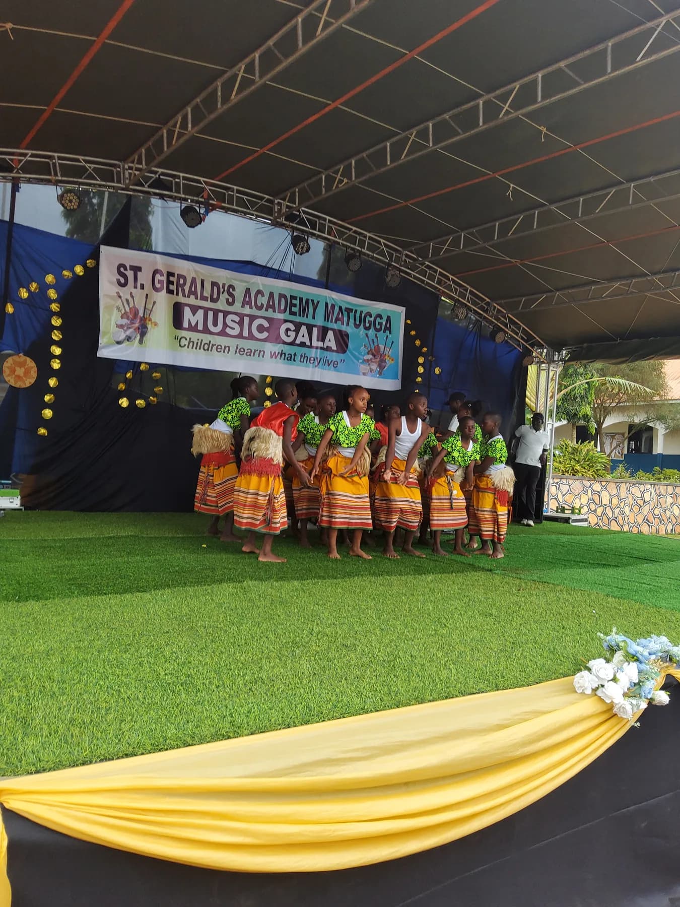 Traditional dancers in green tops and yellow striped skirts gathered in a close circle